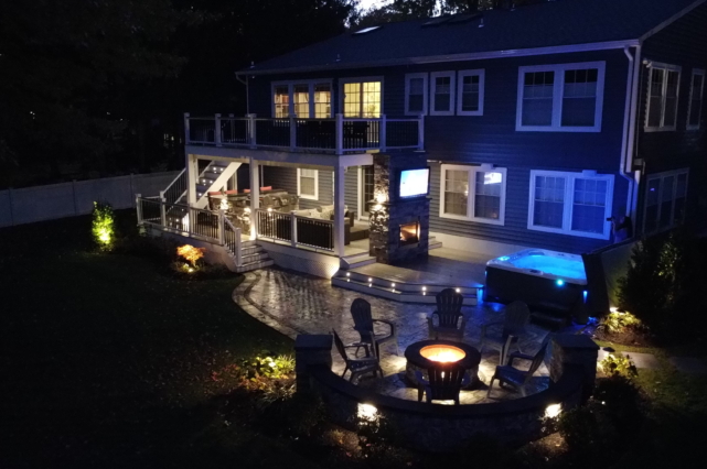 A nighttime shot of a house with a brand new stone deck surrounded by small stake lights