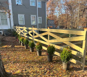 A brand new wooden custom fence lining a backyard with small potted plants