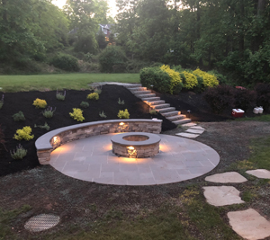 Early evening photo of a stone firepit and stairs surrounded by newly planted flowers and bushes