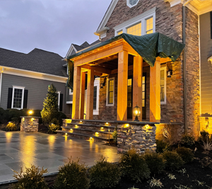 A large stone home in the evening illuminated by small, decorative landscaping lights 